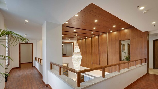 A modern interior with a wooden ceiling, a chandelier, and a staircase with a glass railing.