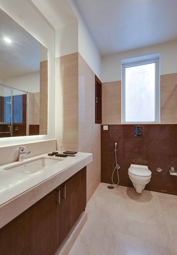 Un baño moderno con un espejo grande, un lavamanos, un inodoro y una ducha.