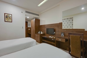A hotel room with two beds, a TV, a desk with a chair, and a mirror. - Shahpura Residency (Jaipur)