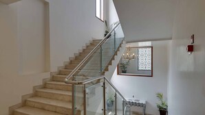 A modern staircase with glass railings and a chandelier.