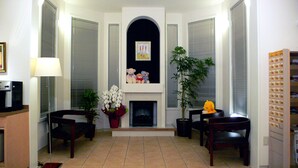 A living room with a fireplace, two chairs, a table, a sofa, a lamp, and a potted plant. - Family Lodge Hatagoya Fujitsuru (Tsuru)