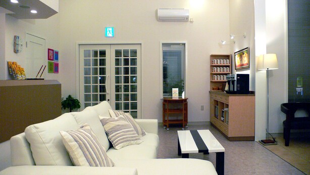 A hotel lobby with a sofa, a coffee table, a reception desk, and a small kitchenette area. - Family Lodge Hatagoya Fujitsuru (Tsuru)