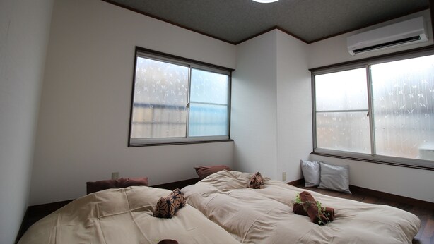 A bedroom with two beds, a ceiling light, and an air conditioning unit.