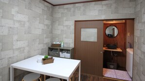 A small, compact room with a white table, a wooden door, a mirror, and a sink.
