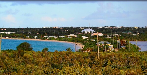 A coastal area with a beach, houses, and a large dome-shaped building.