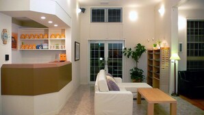 A reception area with a counter, white sofas, a wooden table, a potted plant, and a bookshelf. - Family Lodge Hatagoya Kanazawa Uchinada (Uchinada)