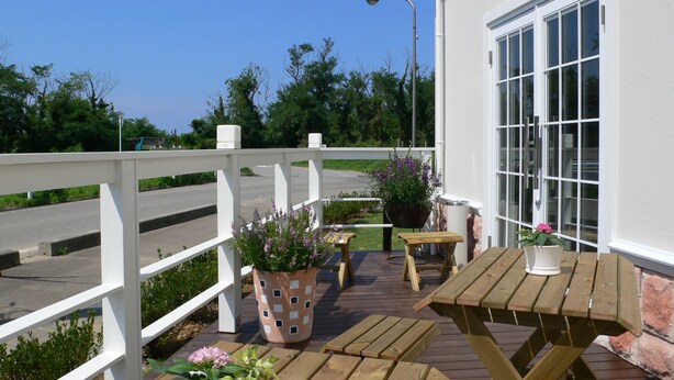 A wooden deck with a white railing, a table, and potted plants. - Family Lodge Hatagoya Kanazawa Uchinada (Uchinada)