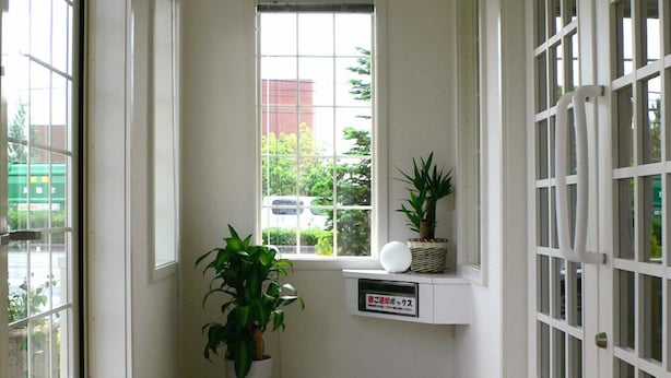 A hallway with a large window, a potted plant, a welcome mat, and a small shelf with a plant. - Family Lodge Hatagoya Takamatsu (Takamatsu)