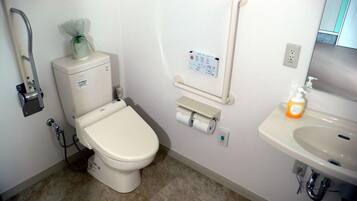 A bathroom with a toilet, a hand dryer, a paper towel dispenser, a soap dispenser, and a sink.