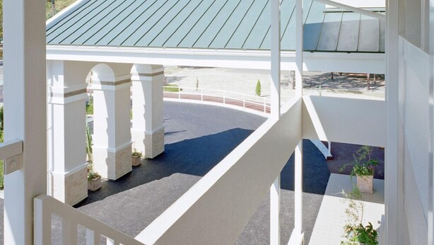 A staircase with white railings leading to a covered outdoor area with a green roof.