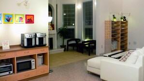 A living room with a white sofa, a coffee machine, a microwave, and a plant.