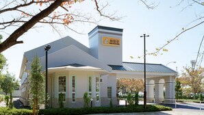 A modern building with a flat roof, large windows, and a sign indicating it is a hotel.