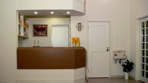 A reception area with a reception desk, a clock, a door, and a small plant.