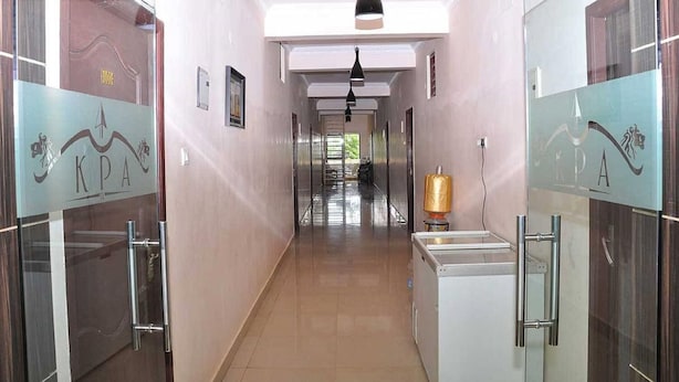 A hotel corridor with glass doors on both sides, a central hallway, and a ceiling light. - KPA Grand Palace (Sriperumbudur)