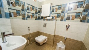 A bathroom with a sink, toilet, and shower. The walls are tiled with a geometric pattern.