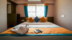 Hotelkamer met een bed, raam met gordijnen, een wandairco en een handdoek op het bed.