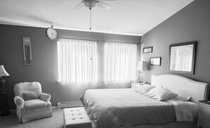 A bedroom with a bed, a chair, a nightstand, a lamp, a clock, and curtains. - Million Dollar View, seasonal pool, close activities w/in 2-5 miles. Yes, pets! (Grand Junction)
