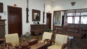 A traditional room with wooden furniture, a large mirror, and a painting on the wall. - Sultan Guest House & Resto Tulungagung (Tulungagung)