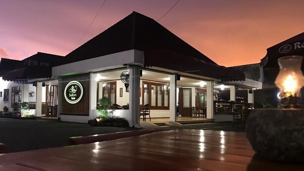 A restaurant with a neon sign, outdoor seating, and a well-lit entrance. - Sultan Guest House & Resto Tulungagung (Tulungagung)