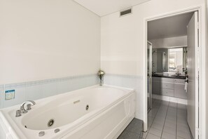 A bathroom with a white bathtub, a shower, and a sink. - Apartment R113 - a secluded beachside retreat! (Scarborough)