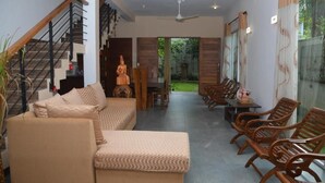 A modern living room with a sofa, wooden chairs, a statue, and a staircase. - Kelaniya Heritage (Kiribathgoda)