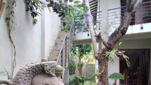 A courtyard with a stone elephant sculpture, a staircase, and various plants. - Kelaniya Heritage (Kiribathgoda)