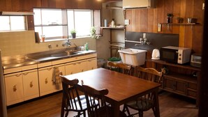 A kitchen with wooden cabinets, a sink, a microwave, and a dining table with chairs. - Guest house tokonoma - Hostel (Kamijima)