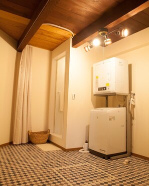 Cozy laundry area with a wall-mounted heater, washing machine, and storage basket.