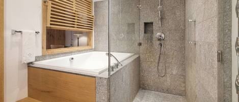 Een moderne badkamer met een vrijstaand bad, een douche met glazen wanden en een houten bankje.
