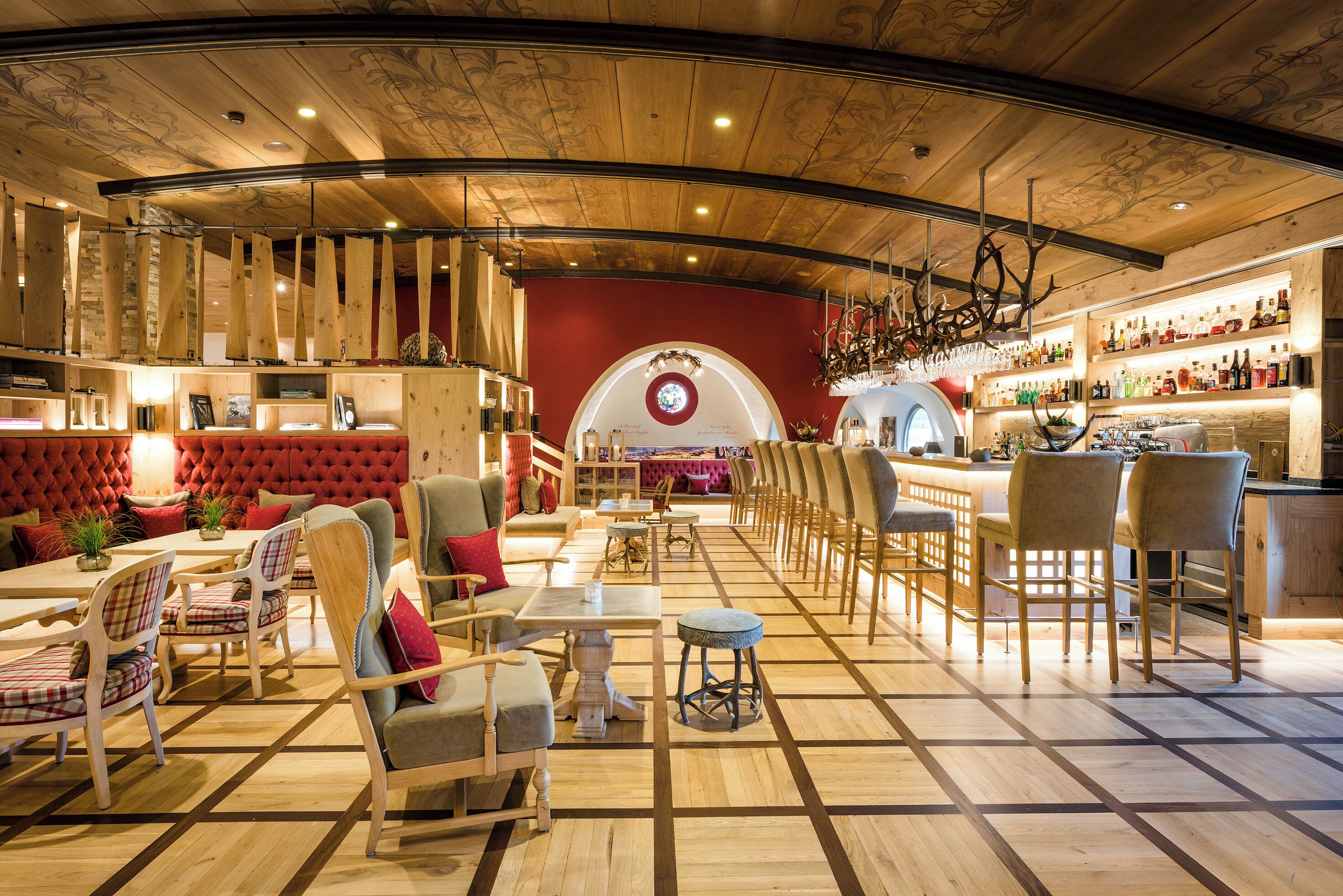 Ein Restaurant mit Holzbalkendecke, roten Wänden und einer Theke mit Flaschenregalen.