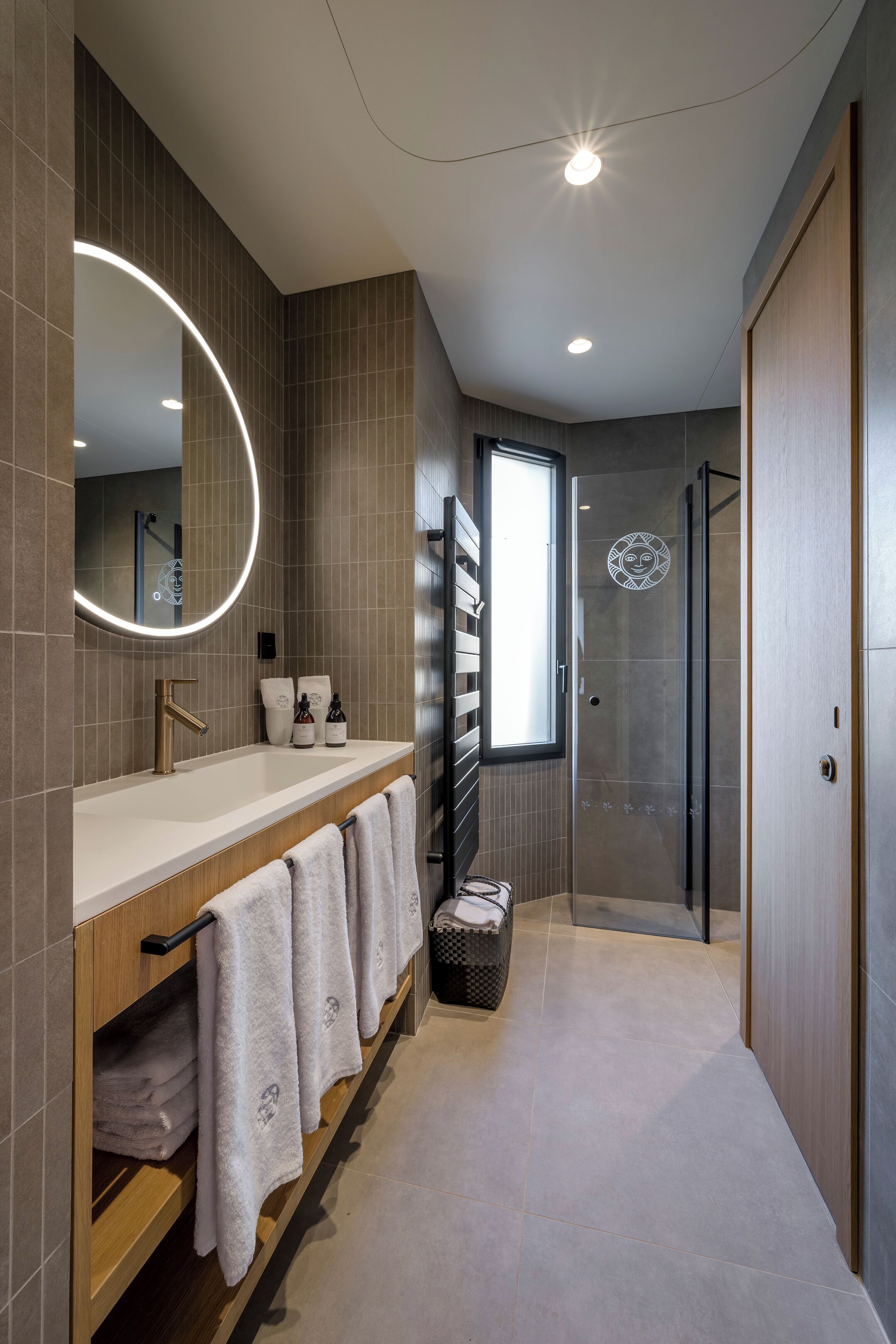 A modern bathroom with a large mirror, a sink, and a shower area.