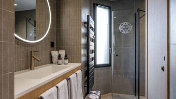 A modern bathroom with a large mirror, a sink, and a shower area.