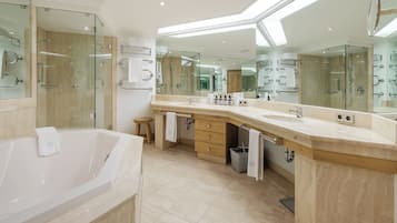 Un baño moderno con una bañera grande, un lavamanos doble con espejo y una zona de ducha con mampara de vidrio.