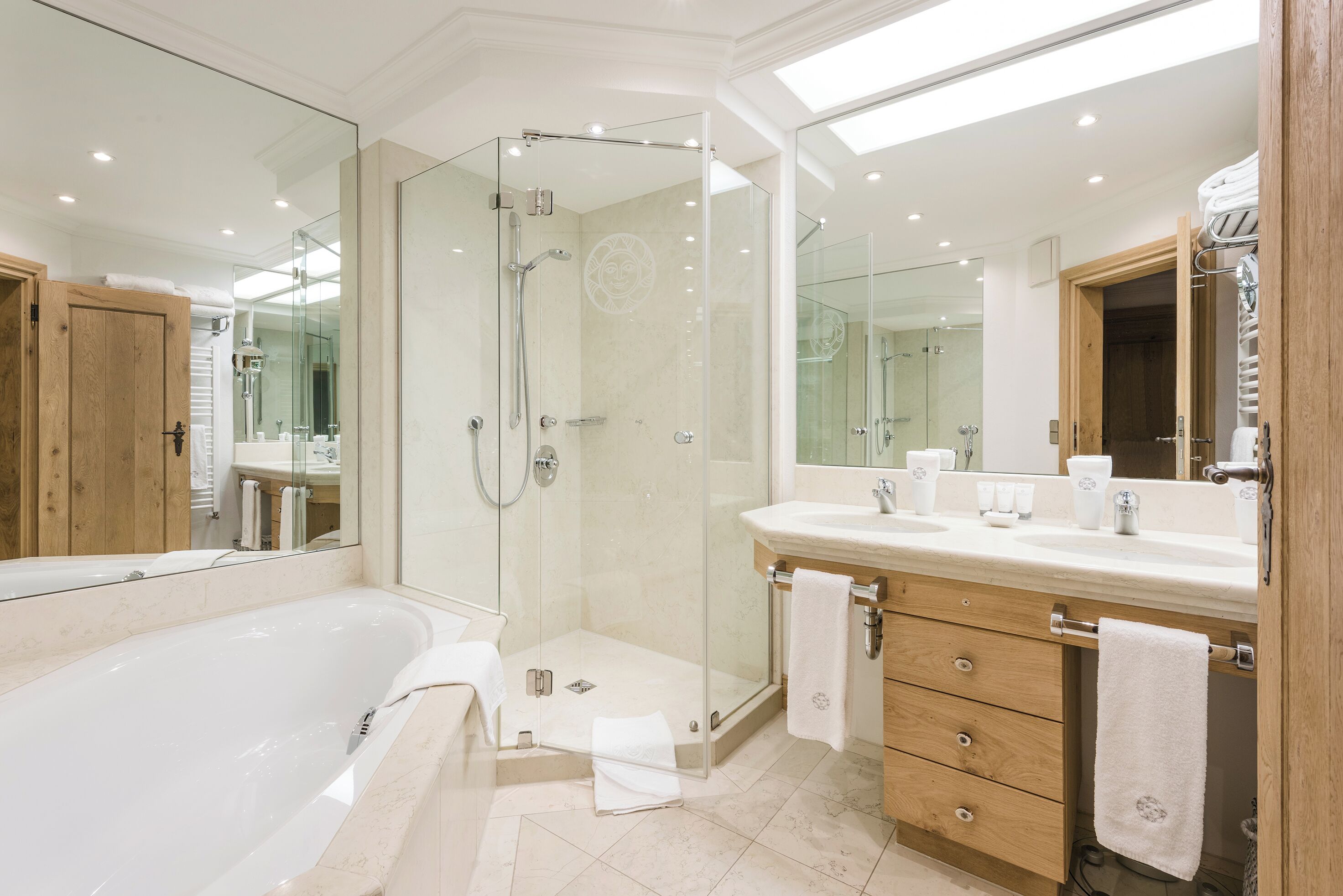 A modern bathroom with a glass-enclosed shower, a large bathtub, and a vanity with a mirror.