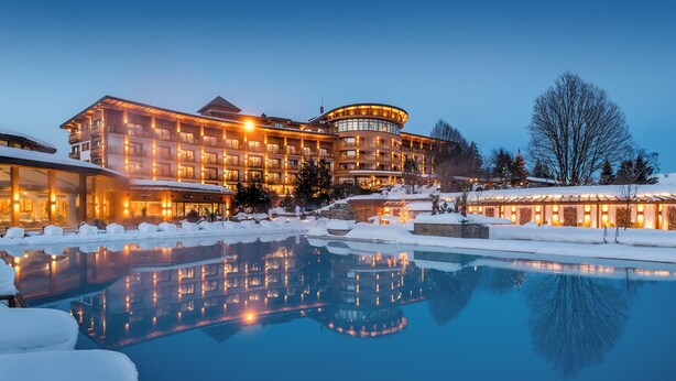 A hotel with a pool surrounded by snow, reflecting the building's lights. - Sonnenalp Resort (Ofterschwang)