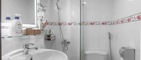 A bathroom with a white sink, toilet, and shower.