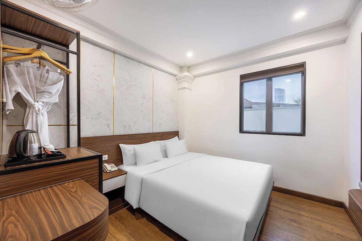 Ein Hotelzimmer mit einem Bett, einem Holztisch, einem Spiegel, einem Fenster und Blick auf die Stadt.