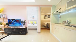 A modern living room with a flat-screen TV, a small coffee table, and a potted plant. - SOGO Dept. Zhongxiao Fuxing MRT (Taipei)