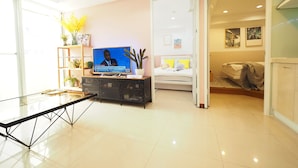 A modern living room with a flat-screen TV, a glass coffee table, a sofa, and a bed. - SOGO Dept. Zhongxiao Fuxing MRT (Taipei)