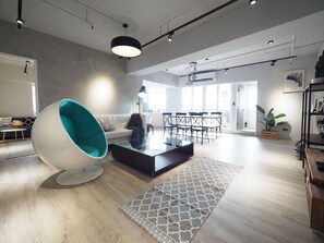 A spacious living area with a modern sofa, a unique egg-shaped chair, a glass coffee table, and a dining area with chairs and a table. - SOGO Dept. Zhongxiao Fuxing MRT (Taipei)