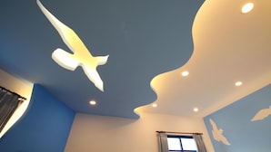 A room with a unique ceiling design featuring a large bird silhouette and recessed lighting. - Easy Stay B&B (Magong)