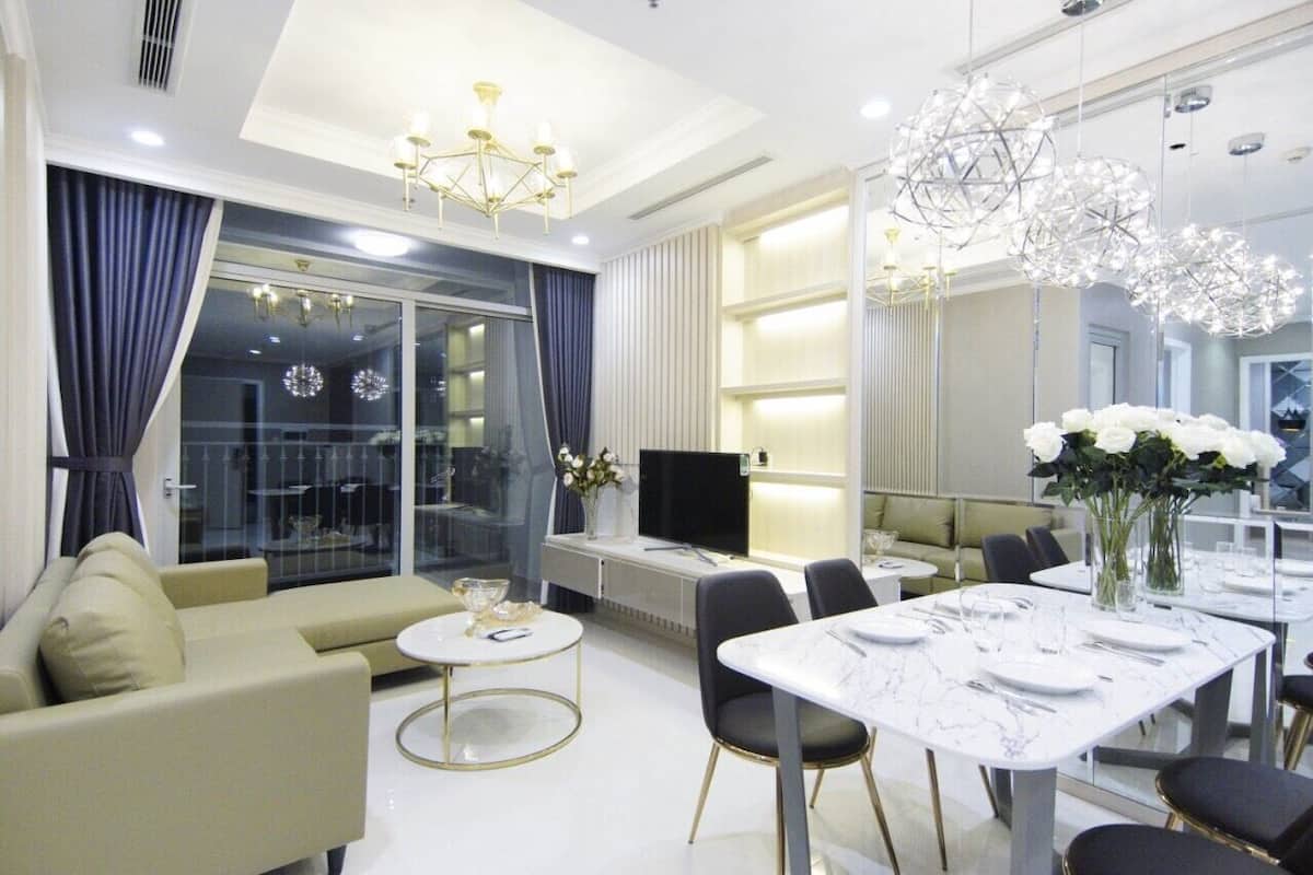 A modern living room with a sofa, a dining table set for two, and a TV.