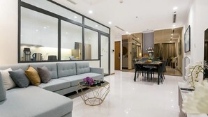 A modern living room with a grey sofa, a coffee table, and a dining area with a table and chairs.