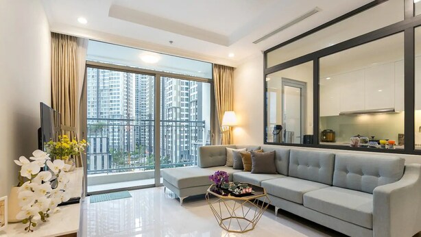 A modern living room with a grey sofa, a coffee table, and a large window with a city view.