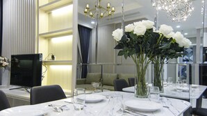 A modern dining area with a marble table, white plates, and a vase of white flowers.