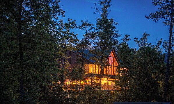 A cabin surrounded by trees at dusk.