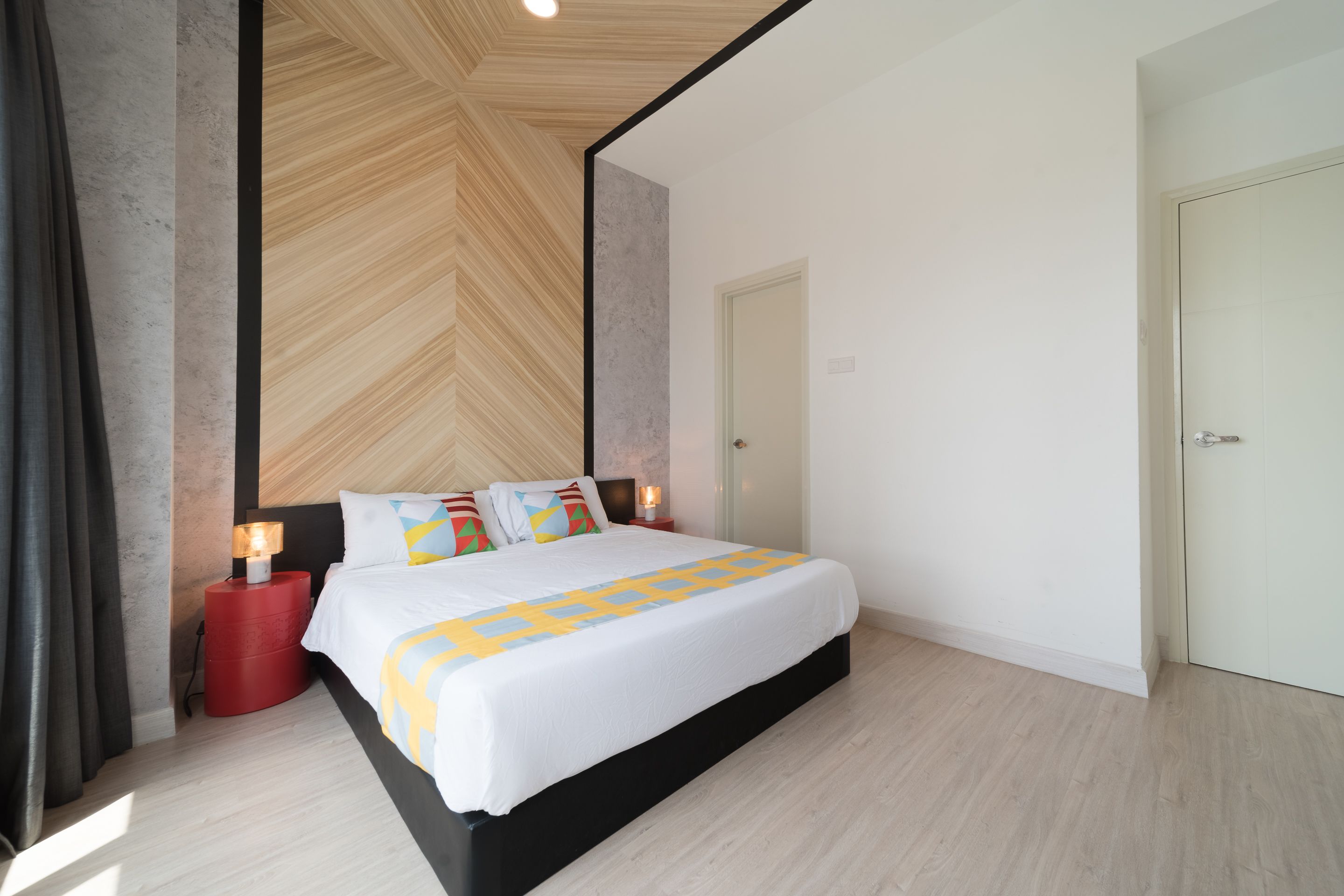 Une chambre moderne avec un grand lit, une table de chevet rouge et un décor en bois au plafond.