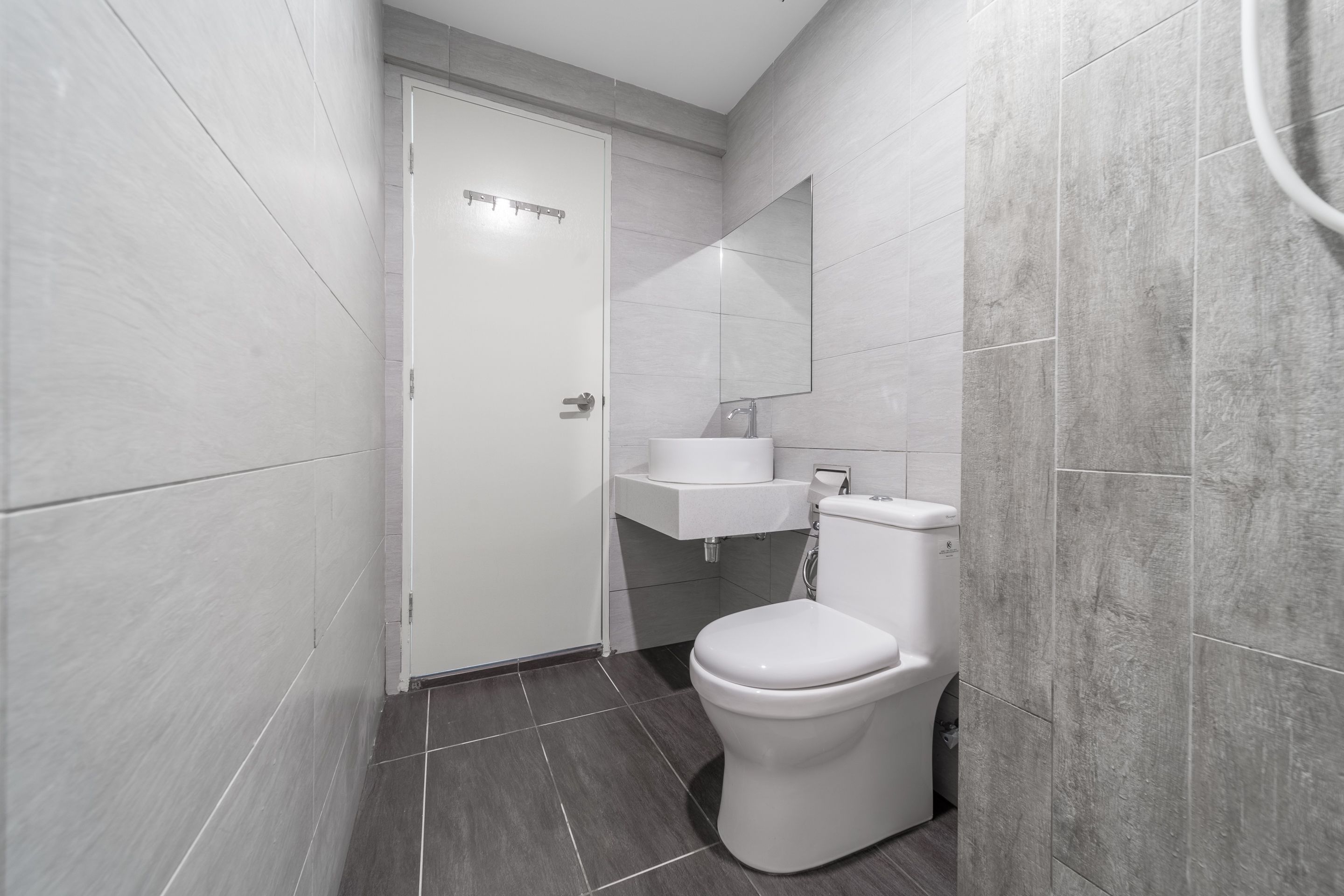 Un baño moderno con un inodoro blanco, un lavabo y un espejo.