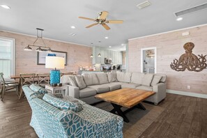 A modern living room with a sectional sofa, a coffee table, and a dining area with chairs and a table. - Lagoon Views | Steps to Gulf Access | Community Pool and Pier (gulf shores)