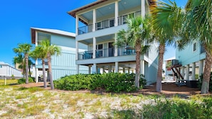 A multi-story hotel with balconies, palm trees, and a sandy ground. - Lagoon Views | Steps to Gulf Access | Community Pool and Pier (gulf shores)
